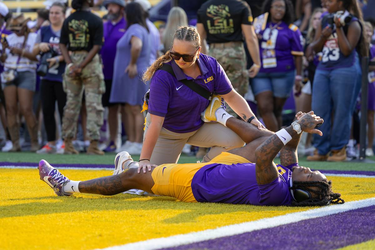 Student athletic trainer helps stretch a football player Student athletic trainer helps stretch a football player