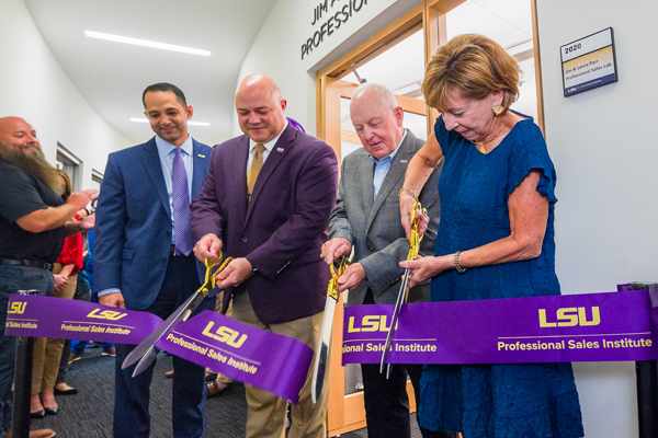 People cut ribbon outside room