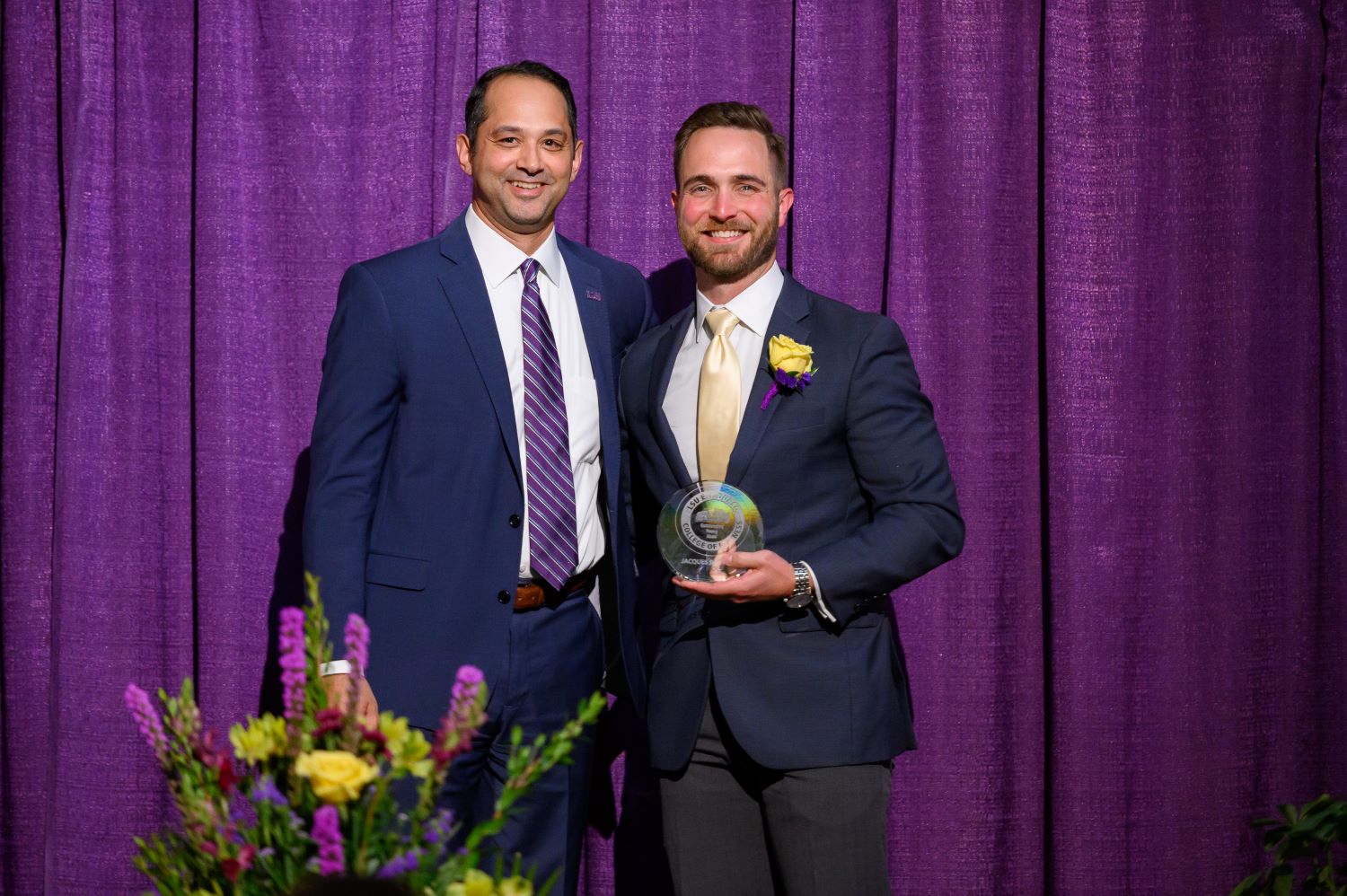 Jacques Bourque and Dean Llorens on stage holding an award