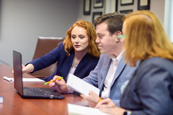 Executive in a conference room one is pointing to a laptop scrren.