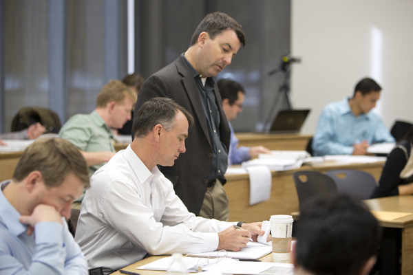 Professor looks over students shoulder as he works on an assignment. 