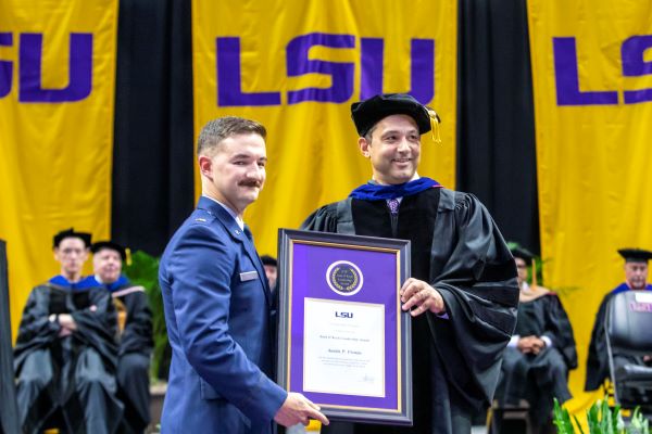 man in military suit receives framed award from dean