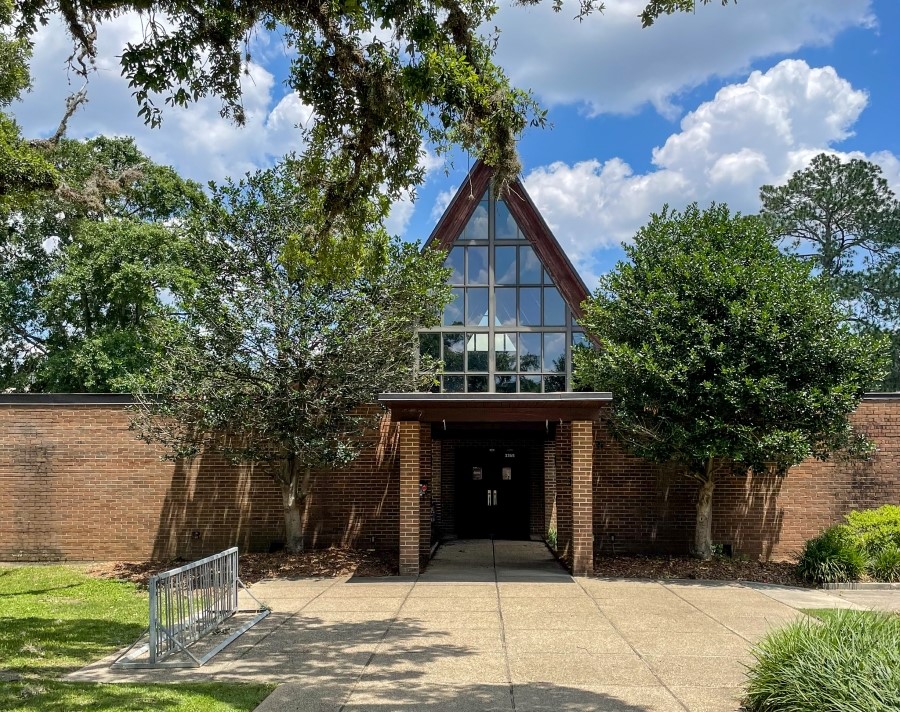 tall building with glass windows and a yard full of trees