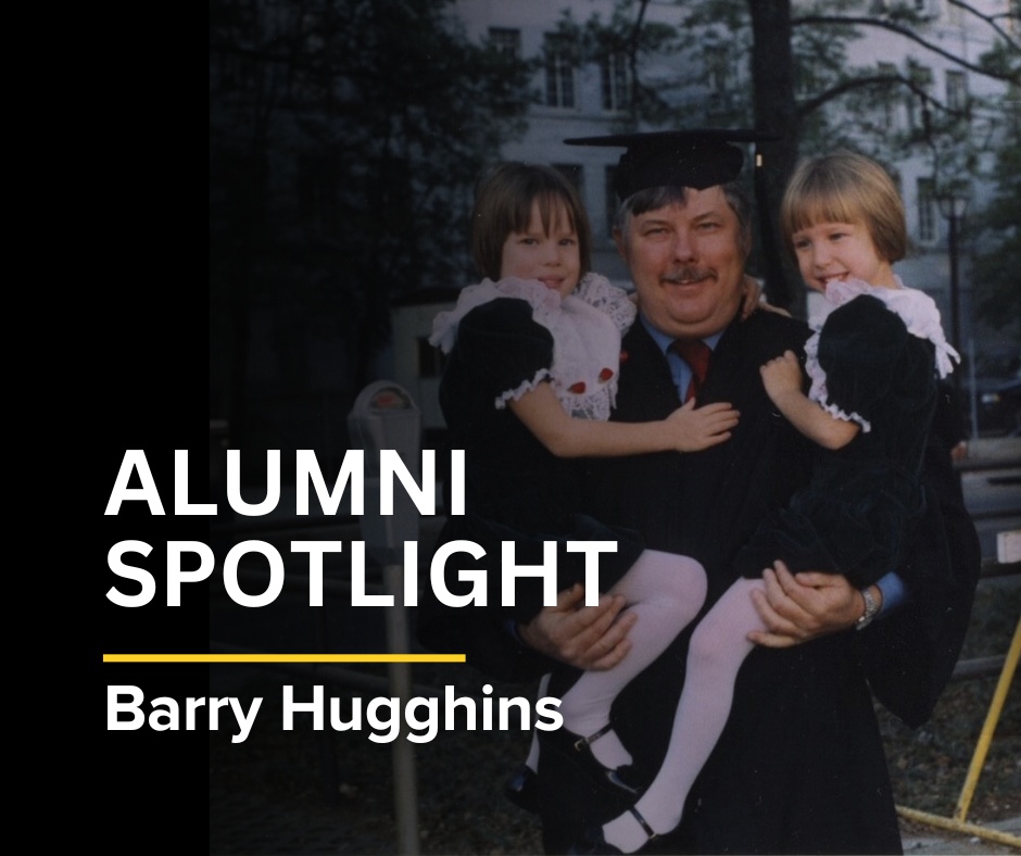 Barry Hugghins holding twin daughters at graduation