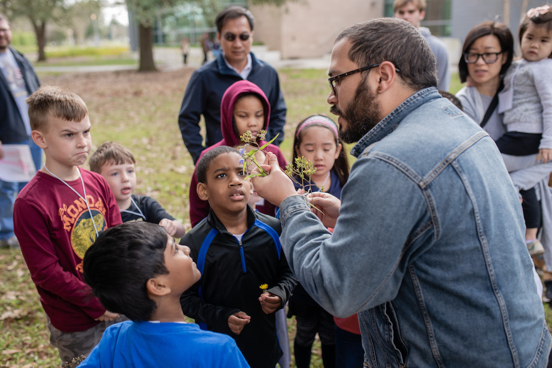 LSU Science STEM Story Time participants participating in an outdoor scavenger hunt with a PhD student.